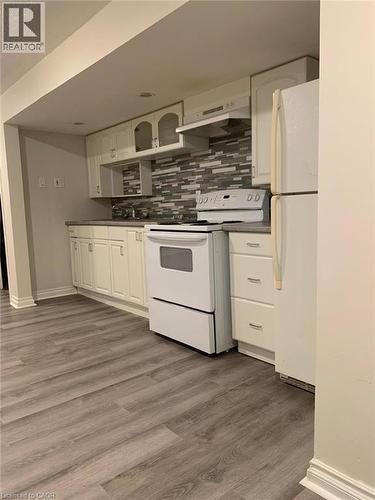 Kitchen featuring white cabinetry, gray and white tile backsplash, white appliances, and wood-finish flooring - 58 Farrier Drive Unit# Basement, Kitchener, ON - Indoor Photo Showing Kitchen