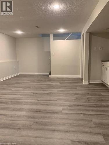 Spacious room featuring wood-finish flooring, recessed lighting, white baseboards, light gray walls, and built-in white cabinetry with a light-toned countertop - 58 Farrier Drive Unit# Basement, Kitchener, ON - Indoor Photo Showing Other Room