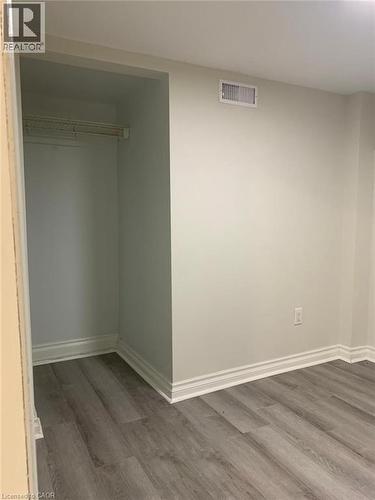Recessed closet with a single hanging rod, grey wood-finish flooring, white baseboard molding, light-colored walls, and a ceiling-mounted register - 58 Farrier Drive Unit# Basement, Kitchener, ON - Indoor Photo Showing Other Room