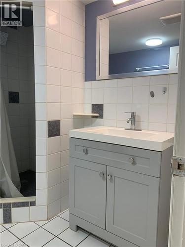 Bathroom featuring a gray vanity with integrated sink, chrome faucet, and white tiled walls with dark gray accents - 58 Farrier Drive Unit# Basement, Kitchener, ON - Indoor Photo Showing Bathroom