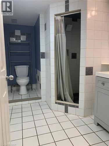 Tiled bathroom featuring a walk-in shower with a rainfall showerhead, a toilet alcove, and a light gray vanity with a countertop - 58 Farrier Drive Unit# Basement, Kitchener, ON - Indoor Photo Showing Bathroom