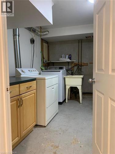 Dedicated utility space featuring a laundry sink, wood-finish cabinetry with dark countertops, and exposed ductwork - 58 Farrier Drive Unit# Basement, Kitchener, ON - Indoor Photo Showing Laundry Room