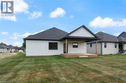 Contemporary architectural design featuring white vertical siding, a covered patio with natural wood decking and support beams, and a dark shingle roof - 