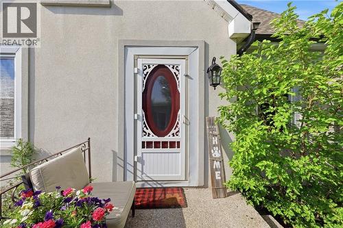 Stucco exterior featuring a white storm door with an oval glass insert and decorative scrollwork - 97 Smith Road, Hamilton, ON 