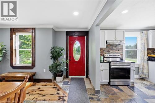 Entryway featuring a bright red door, slate tile flooring, and wood-finish trim - 97 Smith Road, Hamilton, ON 