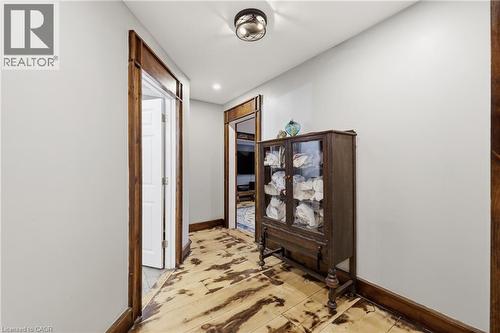 Hallway featuring wood-finish flooring, white walls, and dark wood trim - 97 Smith Road, Hamilton, ON 
