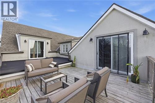 Expansive rooftop deck featuring wood-finish flooring, stucco exterior, multiple sliding glass doors, a flat roof section, and an exterior railing - 97 Smith Road, Hamilton, ON 