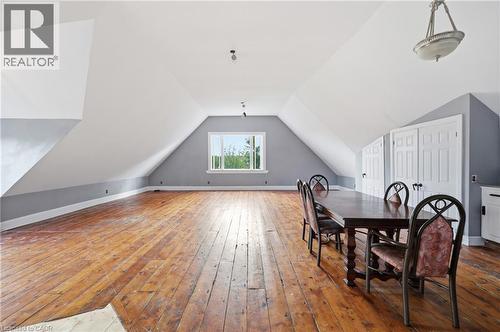 Expansive attic space featuring exposed wood flooring, a window providing natural light, and sloped ceilings - 97 Smith Road, Hamilton, ON 