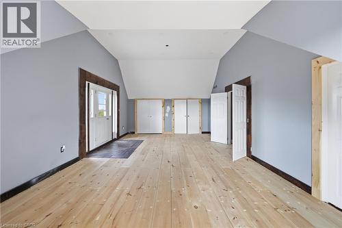 Expansive attic space featuring light wood-finish flooring, vaulted ceilings, light blue walls, and multiple panel doors - 97 Smith Road, Hamilton, ON 