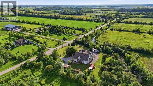 Aerial perspective showcasing expansive green landscapes, a primary residence with a multi-car driveway, surrounding mature trees, and open fields - 97 Smith Road, Hamilton, ON 