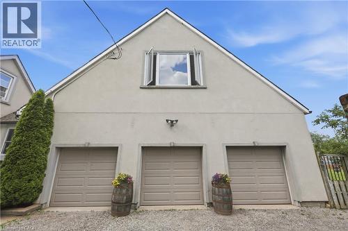 Three-bay garage with panel doors beneath a peaked roofline and a dormer window - 97 Smith Road, Hamilton, ON 