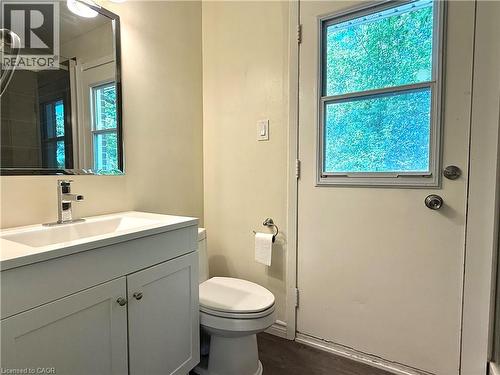 Bathroom featuring a white vanity with integrated sink, chrome faucet, wall-mounted mirror, and wood-finish flooring - 62 Bond Street Unit# 3, Kitchener, ON - Indoor Photo Showing Bathroom