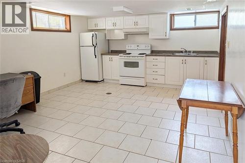 Bright kitchen space featuring white cabinetry, a white electric range, white refrigerator, a double basin sink, and tile flooring - 98 Kipling Road Unit# 2, Hamilton, ON 