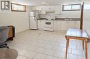 Bright kitchen space featuring white cabinetry, a white electric range, white refrigerator, a double basin sink, and tile flooring - 98 Kipling Road Unit# 2, Hamilton, ON 