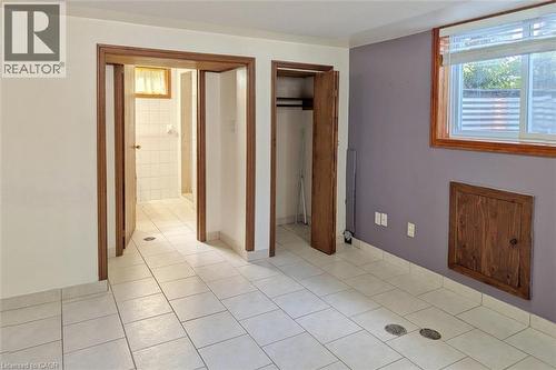 Interior room featuring light-toned tile flooring, white walls, and a purple accent wall - 98 Kipling Road Unit# 2, Hamilton, ON 