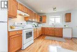 Full kitchen featuring wood-finish cabinetry, white countertops, and wood-finish flooring - 