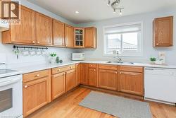 Kitchen featuring wood cabinetry, white countertops, stainless steel sink, and wood-finish flooring - 