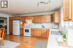 Kitchen featuring wood-finish flooring, white countertops, and light wood cabinetry - 