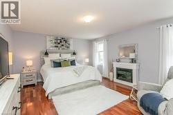 Spacious room featuring wood-finish flooring, light gray walls, and a built-in electric fireplace with a white mantel - 