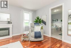 Hardwood flooring extends throughout this room, featuring a white fireplace mantel with an electric insert - 