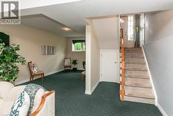 Carpeted staircase with wood handrail, leading to a paneled door with glass inserts - 