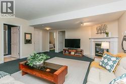 Spacious recreation area featuring a corner-set fireplace with a white mantel, recessed lighting, and multiple access points to additional rooms - 