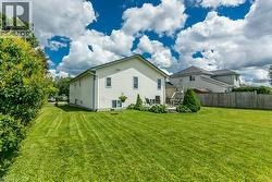 Expansive grassy yard area with mature perimeter foliage, a concrete patio, and a tiered wood deck - 