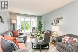 Living room featuring a large bay window, light blue walls, wood-finish flooring, and recessed ceiling lighting - 