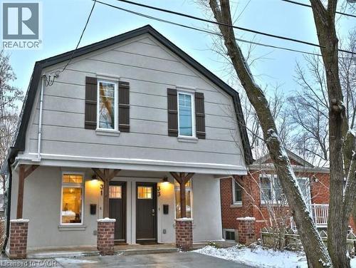 Gambrel-style exterior featuring light gray stucco siding and a dark roof - 33 Hawthorne Avenue, Hamilton, ON 