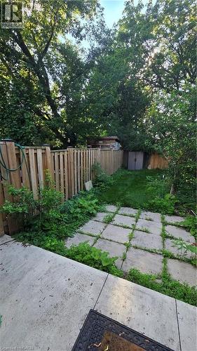 Private backyard space featuring a concrete patio area, square paver pathway, and wood fencing - 33 Hawthorne Avenue, Hamilton, ON 