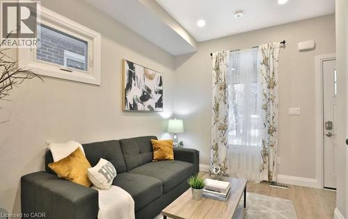 Living space featuring wood-finish flooring, recessed ceiling lighting, and a white entry door with frosted glass inserts - 33 Hawthorne Avenue, Hamilton, ON 
