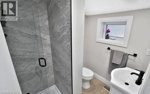 Glass-enclosed shower with large format tile surround, featuring a matte black handle - 33 Hawthorne Avenue, Hamilton, ON 