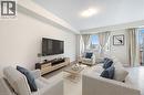 Bright living space featuring a large window, light-colored walls, and mixed flooring with wood-finish and tile sections - 61 Vanilla Trail, Thorold, ON 