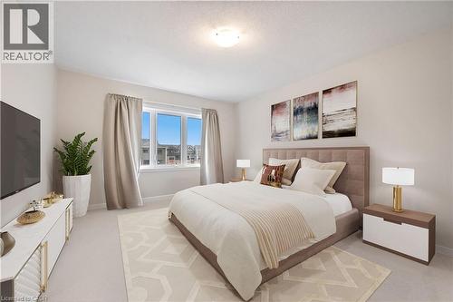 Carpeted bedroom featuring a large window, neutral wall tones, a ceiling-mounted light fixture, and a built-in entertainment console - 61 Vanilla Trail, Thorold, ON 