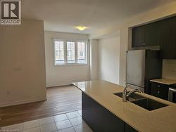 Kitchen with appliances with stainless steel finishes, light tile patterned floors, light stone countertops, modern cabinets, and dark cabinetry - 