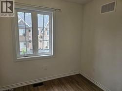 Spare room featuring baseboards and dark wood-style flooring - 