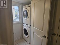 Laundry room featuring light tile patterned floors and stacked washer / drying machine - 