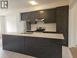 Kitchen with modern cabinets, appliances with stainless steel finishes, a kitchen island with sink, and dark brown cabinetry - 