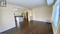 Spacious room featuring rich wood-finish flooring and light-toned walls - 