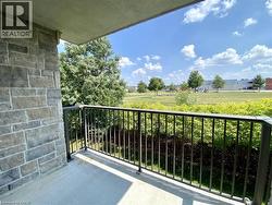 Balcony featuring stone exterior, black metal railing, concrete flooring, and a green landscape backdrop - 