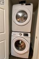 Dedicated laundry closet featuring a stacked white front-load washer and dryer set, dark tile flooring, and white paneled bifold doors - 
