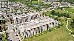Multi-story residential buildings featuring balconies, surrounded by green spaces and paved pathways - 