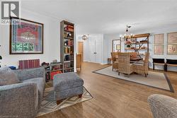 Open-concept living area featuring wood-finish flooring, built-in shelving, a chandelier, and double panel doors - 