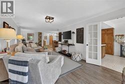 Open-concept living area featuring wood-finish flooring, white crown molding, and a modern flush-mount ceiling light fixture - 