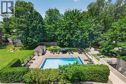 Outdoor swimming pool with surrounding paver patio and mature tree landscaping - 