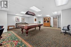 Recreational space featuring a billiards table with an overhead light fixture, recessed lighting, and patterned carpet flooring - 