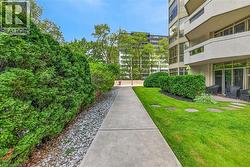 Concrete pathway bordered by manicured hedges and a gravel bed - 