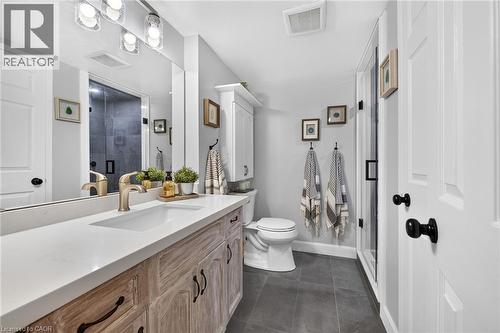 Bathroom featuring a vanity with a light wood-finish cabinet and white countertop, integrated sink with a gold-tone faucet, and an overhead vanity light fixture - 1237 North Shore Boulevard Unit# 405, Burlington, ON - Indoor Photo Showing Bathroom