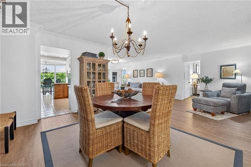 Dining area featuring a circular wood table and an ornate chandelier - 1237 North Shore Boulevard Unit# 405, Burlington, ON - Indoor Photo Showing Dining Room