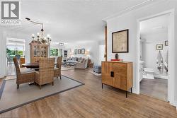 Open-concept interior featuring wood-finish flooring, recessed lighting, crown molding, and a chandelier - 